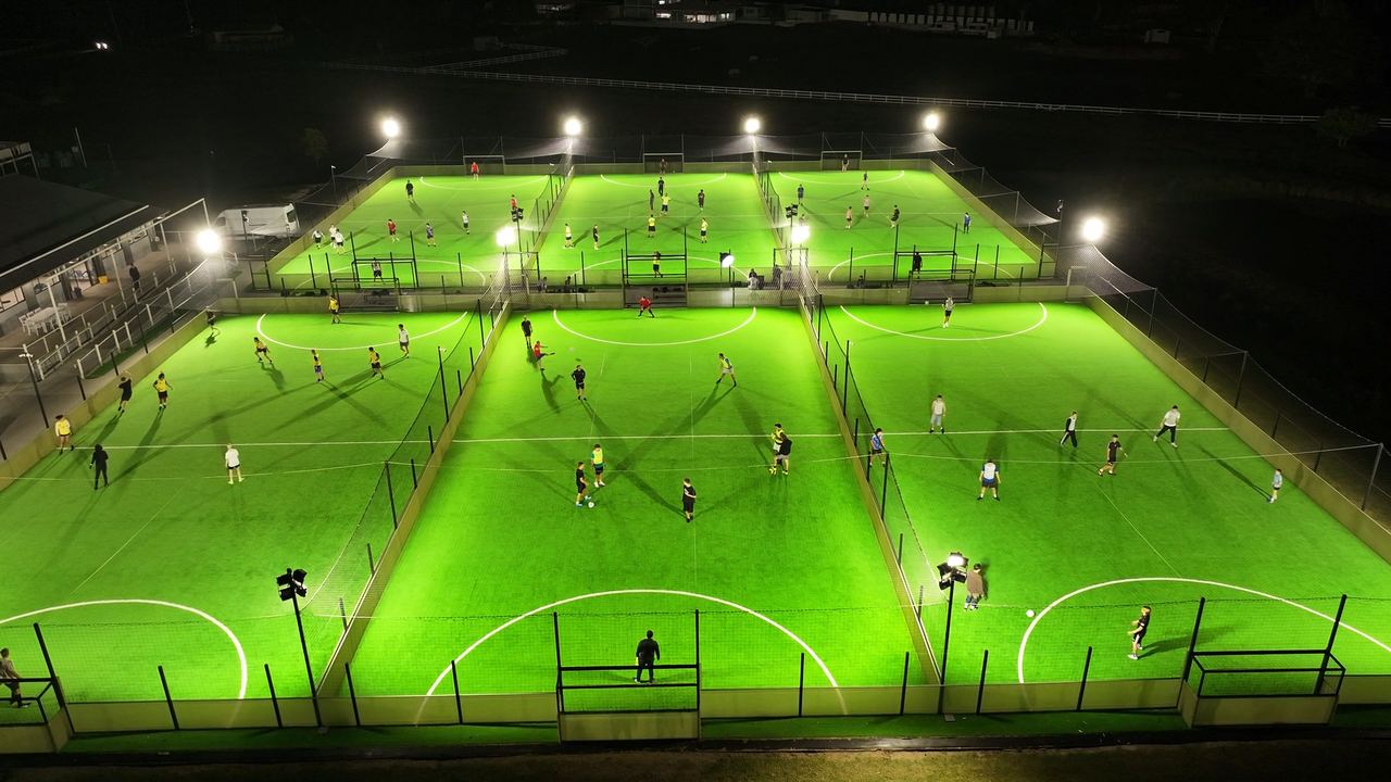 Night drone flight over the floodlit, caged pitches at Street RULZ Football, Tallebudgera
